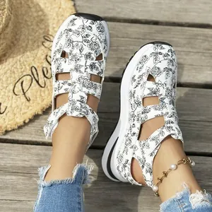 Close-up of women's floral print platform sandals on wooden deck with straw hat