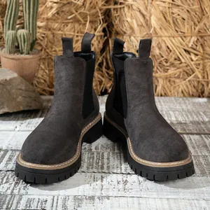 Vista detallada de botas Chelsea de ante con suela de plataforma sobre fondo rústico