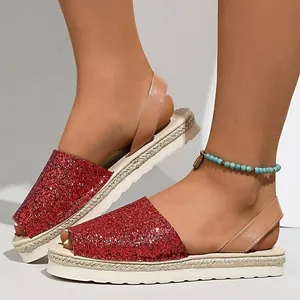 Detail view of red glitter flat platform sandals with open toe and tan ankle strap.