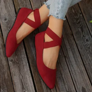 Primer plano de bailarinas rojas de gamuza con punta y correas cruzadas elásticas