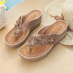 Close-up of brown platform wedge flip-flops featuring elegant flower embellishments