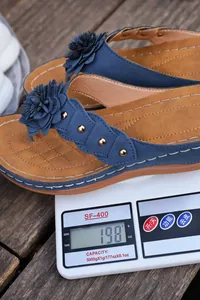 Detailopname van blauwe teenslippers met bloem en klinknagels op een weegschaal