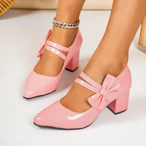 Close-up of stylish pink patent leather chunky heel pumps with a decorative bow detail