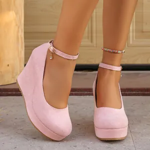 Close-up of pink suede wedge heels with round toe, platform, and delicate ankle strap.