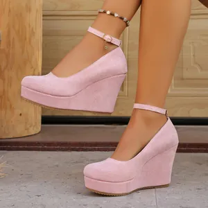Detailed view of pink suede wedge platform shoes with an adjustable ankle strap.