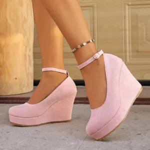 Detail shot of elegant pink suede wedge heels with a secure ankle strap buckle.