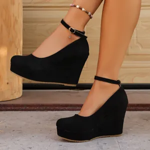 Detail shot of black suede wedge heels with platform and ankle strap