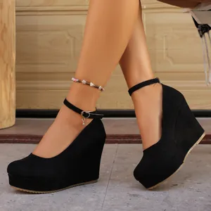 Detailed side view of black suede platform wedge heels with ankle strap design