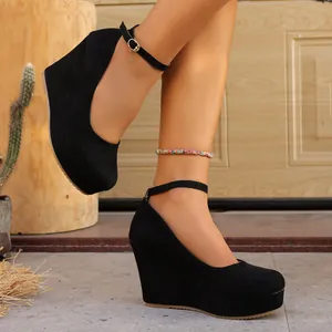 Black suede wedge heels featuring a round toe, platform, and adjustable ankle strap
