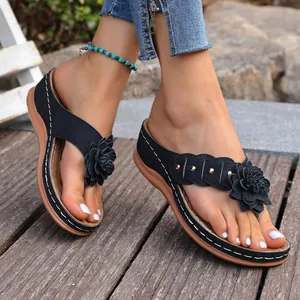 Gedetailleerd beeld van comfortabele dames wedge slippers met bloem- en klinknagelaccenten