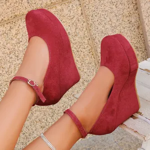 Detail view of stylish burgundy suede wedge pumps featuring an adjustable ankle strap