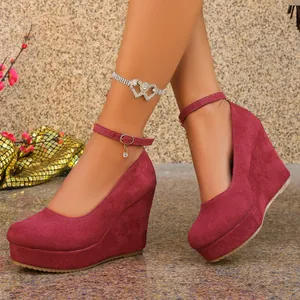Detail of burgundy suede wedge heels featuring a round toe and adjustable ankle strap