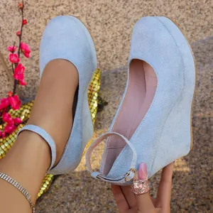 Close-up of light blue suede wedge high heels featuring an elegant ankle strap with a charm