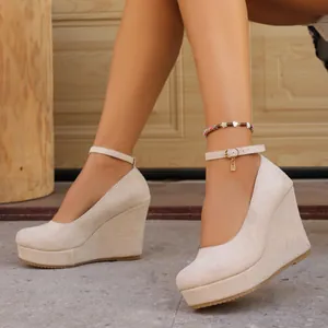 Detail view of cream suede wedge platform heels featuring an adjustable ankle strap.