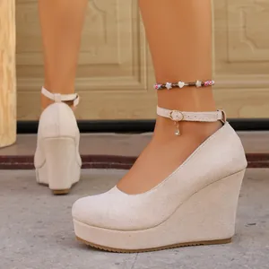 Detailed view of beige suede wedge shoes with round toe and ankle strap design