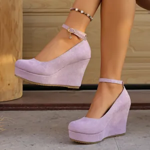 Close-up view of purple suede wedge heels with ankle strap and platform on a model