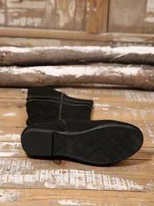 Close-up detail of non-slip rubber sole and suede finish on black slouchy high boots