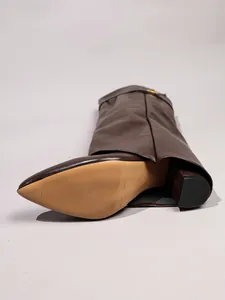 Detailed view of brown pointed-toe pant-leg boots with sturdy block heel and smooth finish.