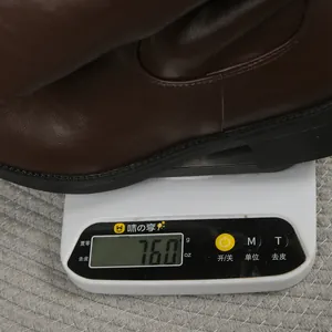 Detailed view of a brown leather riding boot being weighed at 760 grams on a scale
