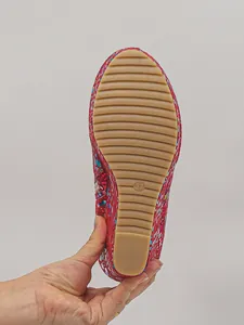 Bottom view of red patterned platform wedge ankle boot showing ridged tan sole detail