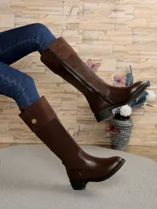 Detailed view of dark brown knee-high riding boots with side zipper and suede trim.