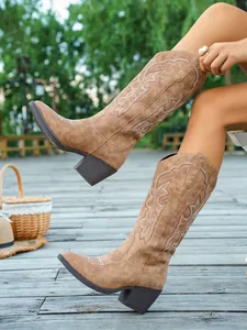 Vue de côté de bottes de cowboy marron vintage avec broderies blanches et talons épais.
