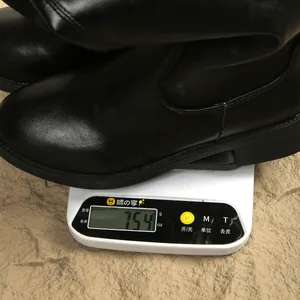 Detail view of a black British style knight boot being weighed on a digital scale