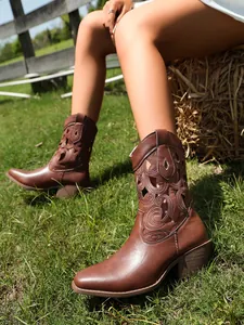 Detail view of retro brown Western boots with hollow-out pattern on grass