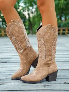 Détail de bottes de cowboy vintage marron clair avec broderie et de larges talons.