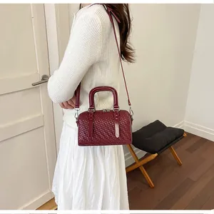 Modell mit einer eleganten weinroten gewebten Boston Bag mit Henkel und Gurt