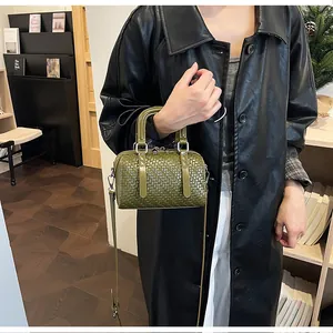 Detailansicht einer dunkelgrünen gewebten Boston-Handtasche, von einem Model getragen