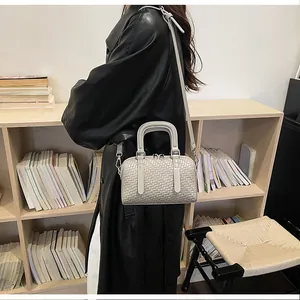 Detailansicht einer eleganten gewebten Boston-Handtasche mit Umhängeriemen.