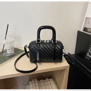 Eleganter schwarzer gewebter Boston-Handtasche auf einem Holzregal für den täglichen Weg.