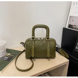 Detailansicht einer olivgrünen gewebten Boston-Handtasche auf einem modernen Regal