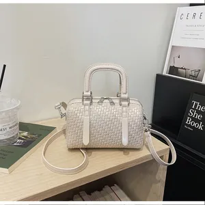 Detaillierte Ansicht einer cremefarbenen gewebten Boston-Handtasche auf Regal