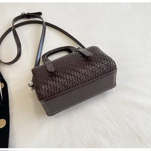 Detailansicht der dunkelbraun gewebten Boston Bag auf cremigem Stoff
