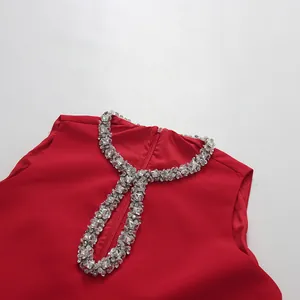 Close-up detail of a red sleeveless dress featuring a luxurious rhinestone neckline.