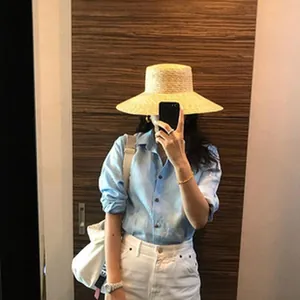 Women's vintage raffia straw hat styled with a blue shirt in a mirror selfie detail shot