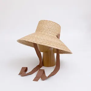 Detailed view of a vintage raffia straw sun hat with a brown ribbon tie on stand.