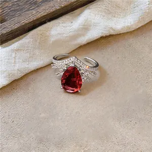 Gedetailleerde opname van een elegante open ring met een grote rode zirkoon in druppelvorm