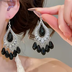 Detailed view of vintage black teardrop tassel earrings with intricate filigree.