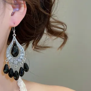 Detailed view of vintage palace style black water drop tassel earrings on model ear