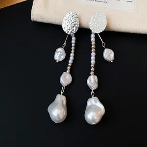 Gros plan de boucles d'oreilles vintage avec métal argenté martelé et perles baroques
