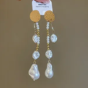 Vue détaillée de boucles d'oreilles vintage en or avec perles baroques blanches étagées.
