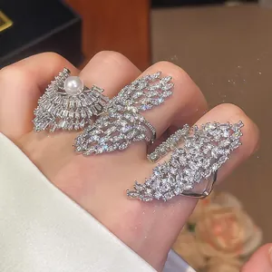 Détail de trois bagues en argent de luxe avec zircons et une perle sur les doigts