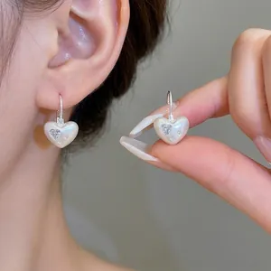 Boucles d'oreilles cœur élégantes avec zircons étincelants portées par un mannequin.