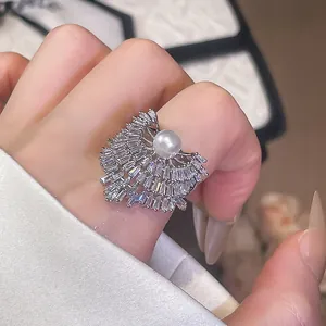 Détail d'une bague ouverte géométrique de luxe avec perle blanche et zircons scintillants