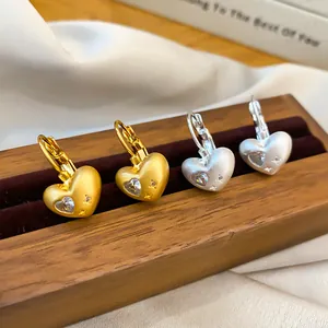 Detail view of gold and silver heart hoop earrings with sparkling zircon stones for women