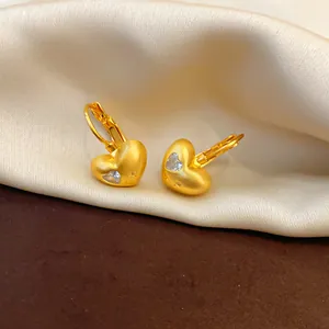 Close-up detail of matte gold finish heart hoop earrings with a clear zircon stone