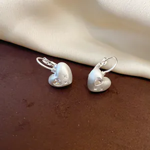 Detail view of elegant matte silver heart earrings with sparkling heart-cut zirconia stones
